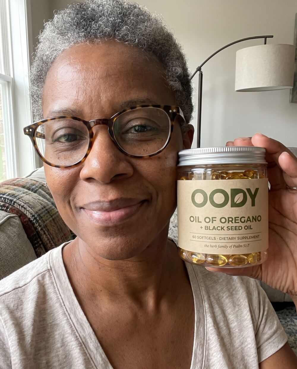Woman in her fifties with glasses holding the OODY jar in her living room