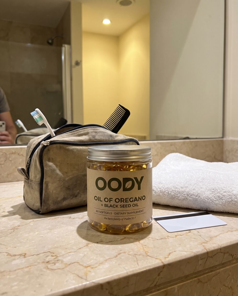 OODY jar beside a toiletry bag on a hotel bathroom counter