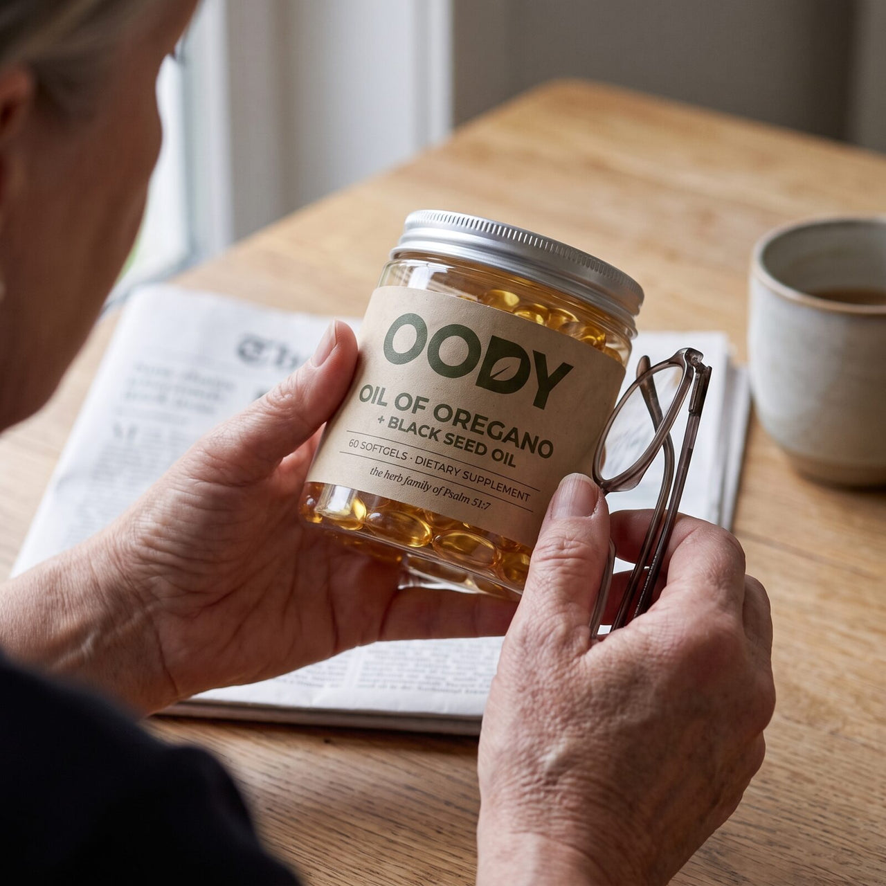 Hands holding the OODY jar and a pair of reading glasses