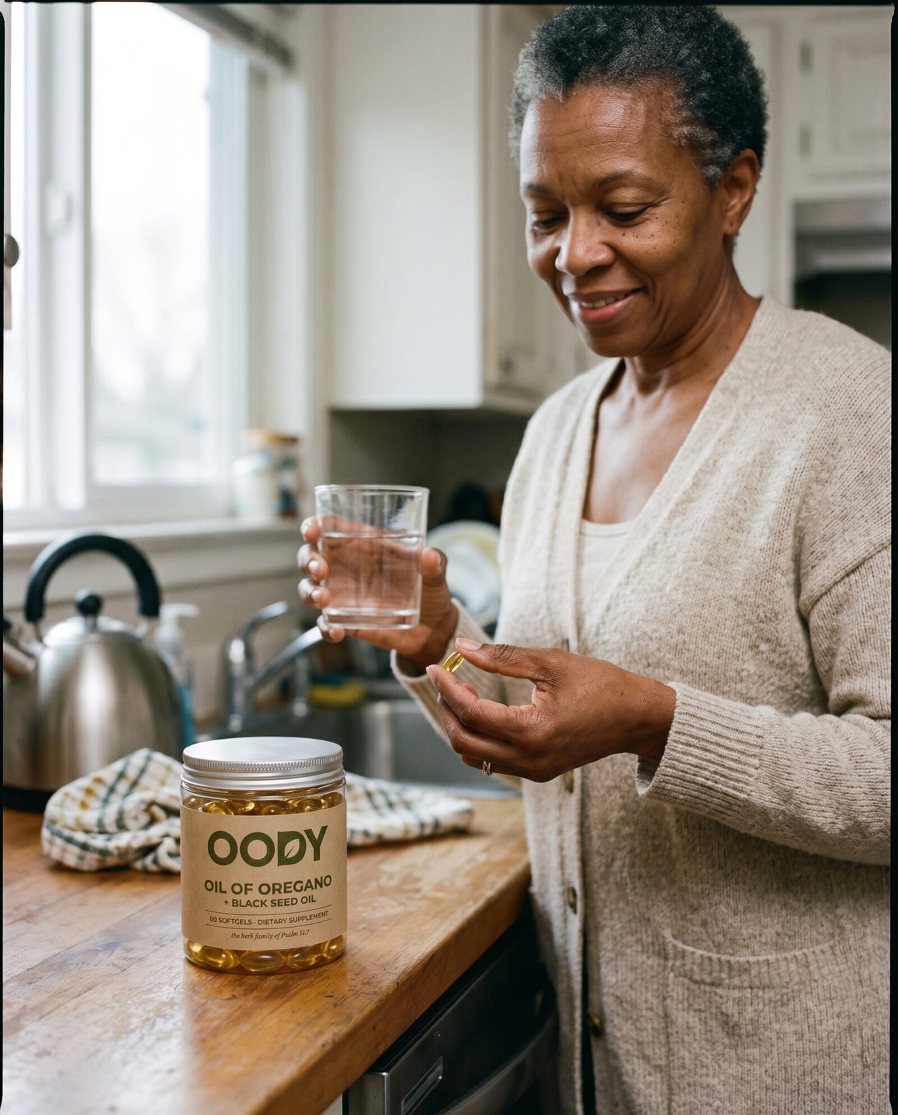 Woman in her sixties taking a softgel with a glass of water in her kitchen