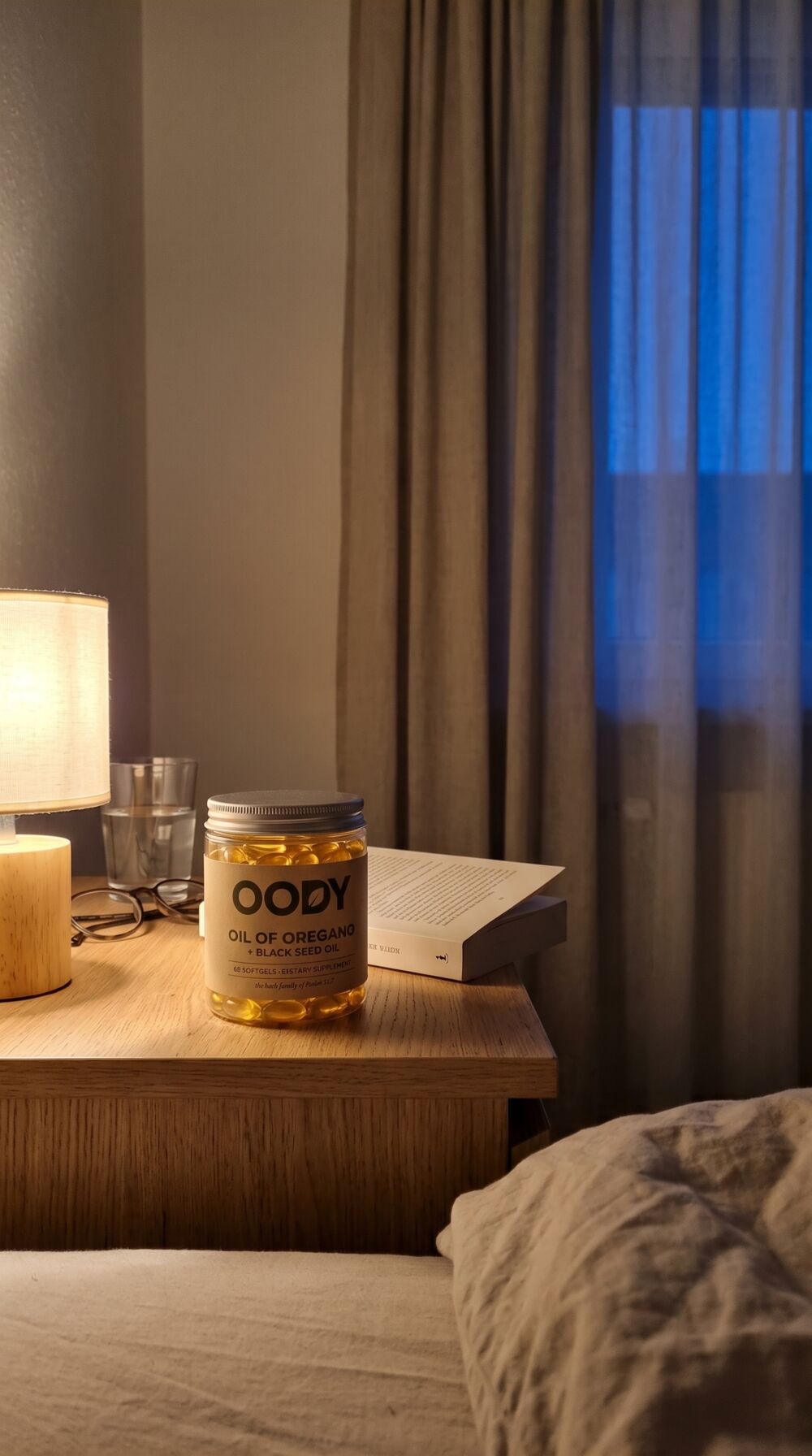 OODY jar on a bedside table beside a lamp and a paperback