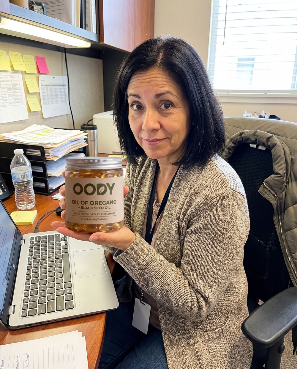 Woman in her fifties holding the OODY jar at her office desk